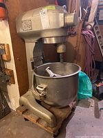 Full side view of Hobart industrial stand mixer with attached mixing bowl and paddle attachment inside bowl.