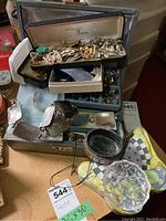 Overall view of multiple jewelry pieces with boxes and small containers, showing variety of costume jewelry including some vintage pieces like brooches and pearl strands.