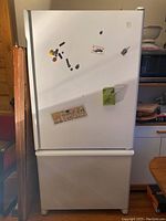 Front view of closed white Maytag Plus refrigerator with magnets on door