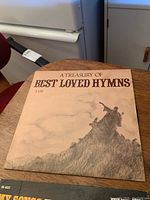 Front cover of 'A Treasury of Best Loved Hymns' showing a sepia-tone artistic illustration with title text.