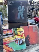 Photo showing three vinyl records with visible cover art: David Bowie Live, A Flock of Seagulls, and U2 single Under A Blood Red Sky.