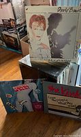 Plastic case containing various vinyl records including David Bowie, Talking Heads, and The Kinks albums.