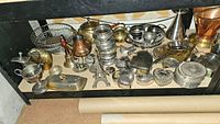 Wide shot showing multiple silver plated, brass, and copper items including small trays, jewelry boxes, coasters, and decorative pieces.