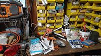 Wide view of workbench cluttered with various tools and hardware, including saws, clamps, measuring tape, and hand tools.