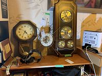 Overall view of two clocks and the Bulova combination meter clock on shelf, with visible price tags and wall background.