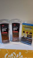 Three unopened leather and vinyl repair kits: two 3M Auto branded kits and one additional kit with blue and yellow packaging.
