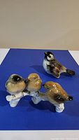 Bird figurines on blue mat, three birds on white branch and single bird visible