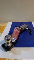 Overall front and side view of the MotoMaster towing ball mount showing the ball attached to the mount and product label.
