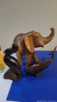 Elephant, whale, and pelican wooden carved animal figures arranged on blue and white background.
