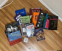 Top-down photo showing a group of 15 books related to film, screenwriting, and business topics spread on a wooden floor.