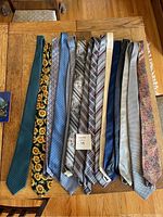 Photo showing all 15 neckties laid out side by side on wooden table, displaying various patterns and colors.