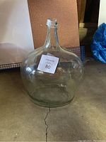 Side view of large clear antique glass jug showing its round bulbous body and narrow neck