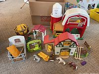 Overview of barn playsets and various horse stalls with animal figures and accessories on carpeted floor