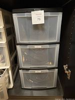 Three stacked plastic storage containers labeled WORK A/V and HOME A/V containing cables.
