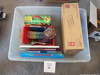 Top view of clear plastic bin containing Magnetiles box, sun stamp educational game, writing guide materials and a Grinch puzzle box inside.