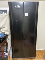 Closed view of large black metal utility cabinet, front with two doors, handles, and key lock.