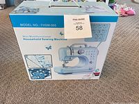 Photo showing the front of the box with the image of the sewing machine, model number FHSM-505, and product name Mini Multifunctional Household Sewing Machine
