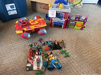 Full lot view with Helicarrier play set, Spider-Man and Green Goblin play sets, and assortment of superhero figures including boxed Spider-Man figure, Wolverine plush, and plastic army men.