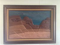 Framed desert landscape raised sand art with rock formations against blue sky, signed Popko.