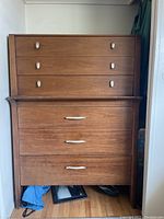 Full view of tall solid wood dresser with two stacked sections and multiple drawers with metal handles