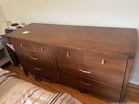 Front view of the vintage solid wood dresser showing six drawers with metal handles and keyholes, visible wear on wood surfaces.