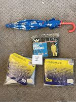 Lot overview showing blue kids umbrella with animal prints, Weather-Rite 2-piece vinyl rainsuit in sealed package, and two packaged large trenchcoat vinyl raincoats labeled Regenmantel.