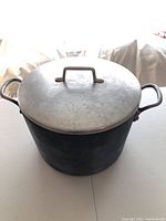 Top view of the large hard anodized pot with lid showing metal handles and pot surface wear
