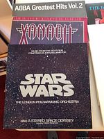 Photo showing top view of vinyl album covers including ABBA Greatest Hits Vol. 2, Xanadu soundtrack, Star Wars soundtrack by John Williams.
