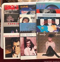 Photo shows front covers of various 80s rock vinyl albums stacked and partially overlapping, including Robert Palmer, Eddie Money, Foreigner, Def Leppard, Cheap Trick, Eagles, Bryan Adams.