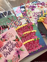 Photo showing multiple colorful gift bags standing upright with various floral and birthday patterns and different sizes