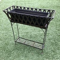 Metal planter box stand with lattice design, copper metal liner inside showing rust, and black plastic drainage planter box placed on grass.