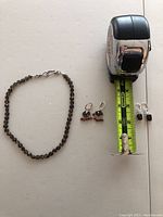 Full lot showing one smoky quartz bead necklace, one pair of dangling smoky quartz earrings with small red beads, and one pair of small smoky quartz stud earrings next to tape measure for scale.