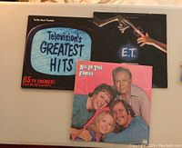 Four vinyl LP albums laid out including Television's Greatest Hits, E.T. soundtrack, and two All in the Family albums.