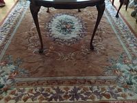 Full view of the floral area rug with table legs on top, showing overall design and color scheme.