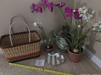 Overview of entire lot showing artificial flowers in pots, decorative dish, and woven basket with measuring tape