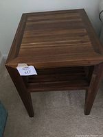 Side view of the Crate & Barrel solid wood mid century modern side table showing the slatted lower shelf and wood grain finish.