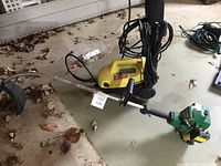 Yellow Karcher electric power washer on floor with black hose and handle, visible dirt and leaves around.