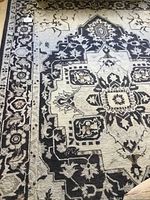 Close-up front image showing the central medallion with black, taupe and gray floral and geometric design on the natural background.
