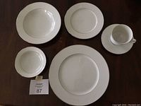 Photo showing various pieces including a dinner plate, salad plate, soup bowl, and fruit bowl arranged on a wooden surface.