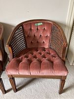 Front view of chair showing tufted velvet upholstery and caned sides with wooden frame.