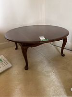 Photo of round cherry wood coffee table top and part of a decorative book nearby.