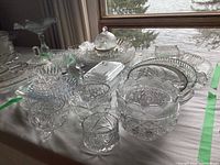 Wide view showing multiple crystal and glass serving items on a table including bowls, trays, butter keepers, and cream and sugar sets.