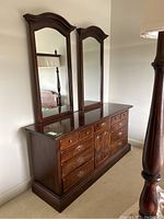 Full view of dresser with two attached mirrors in bedroom
