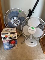 Photo showing two fans and one boxed propane heater; includes a white Classic fan with control buttons at the base, a larger metallic Superior fan, and a box labeled Mr Heater.