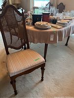 Side chair with wooden framed cane back and striped upholstered seat in front of the dining table.