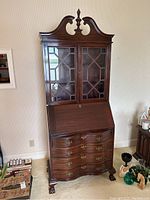 Full front view of the mahogany Chippendale-style secretary desk showing glass fretwork doors, drop-front, serpentine drawers and finial