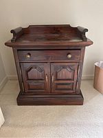 Front view of one Ethan Allen dark wood nightstand showing one drawer and two doors below with brass handles, visible scratches on surface.