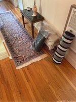 Overview of light blue runner rug laid on hardwood floor with rolled striped mat and dark gray mat beside it