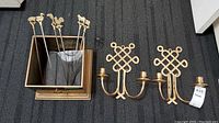 Photo showing brass box with five decorative brass skewers and two brass wall sconces placed on floor