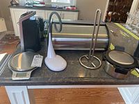 Countertop with various kitchen items from the lot including coffee grinder, hot food container, paper towel holder, scale